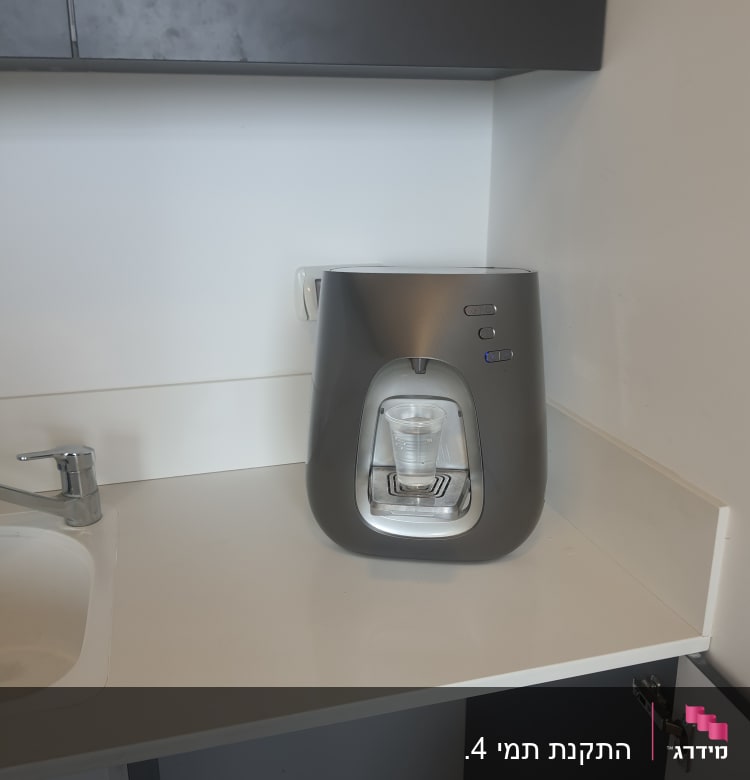 מכשיר מים על השיש ליד כיור פתוח